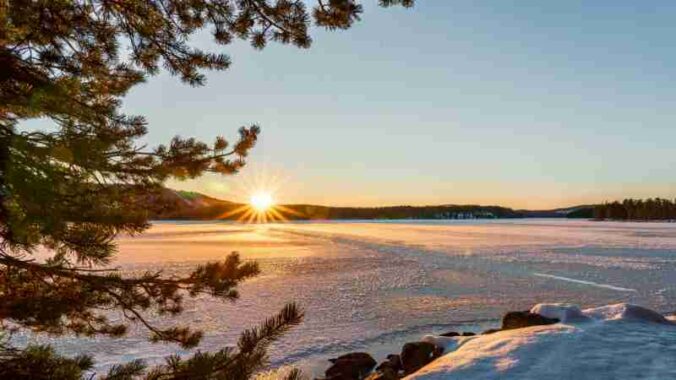 Captivating winter sunrise over a tranquil frozen lake surrounded by snow and pine trees., tags: im - pexel